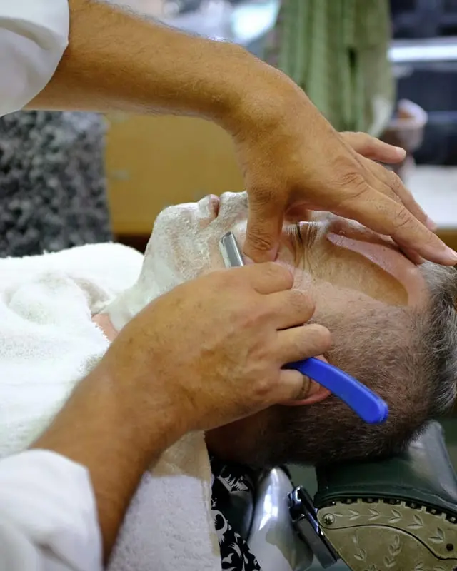 Barbero dando un afeitado clásico a navaja en Esem Barbería Clásica, Madrid
